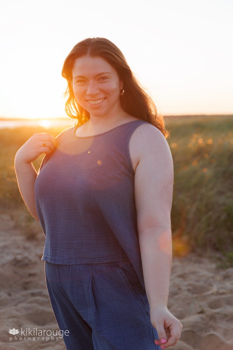 Woman in Blue top and bottoms with sun flare in dunes at sunset