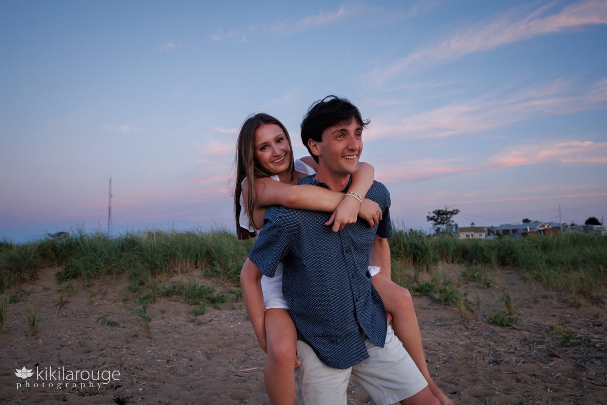 Younger sister on big brother's back smiling at Plum Island beach