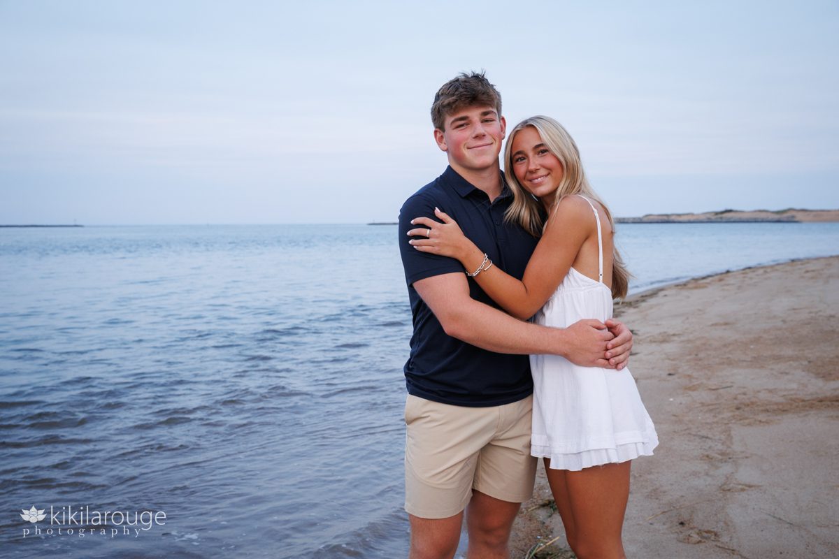 Teen seniors and brothers and sister hugging by water's edge at Plum Island beach