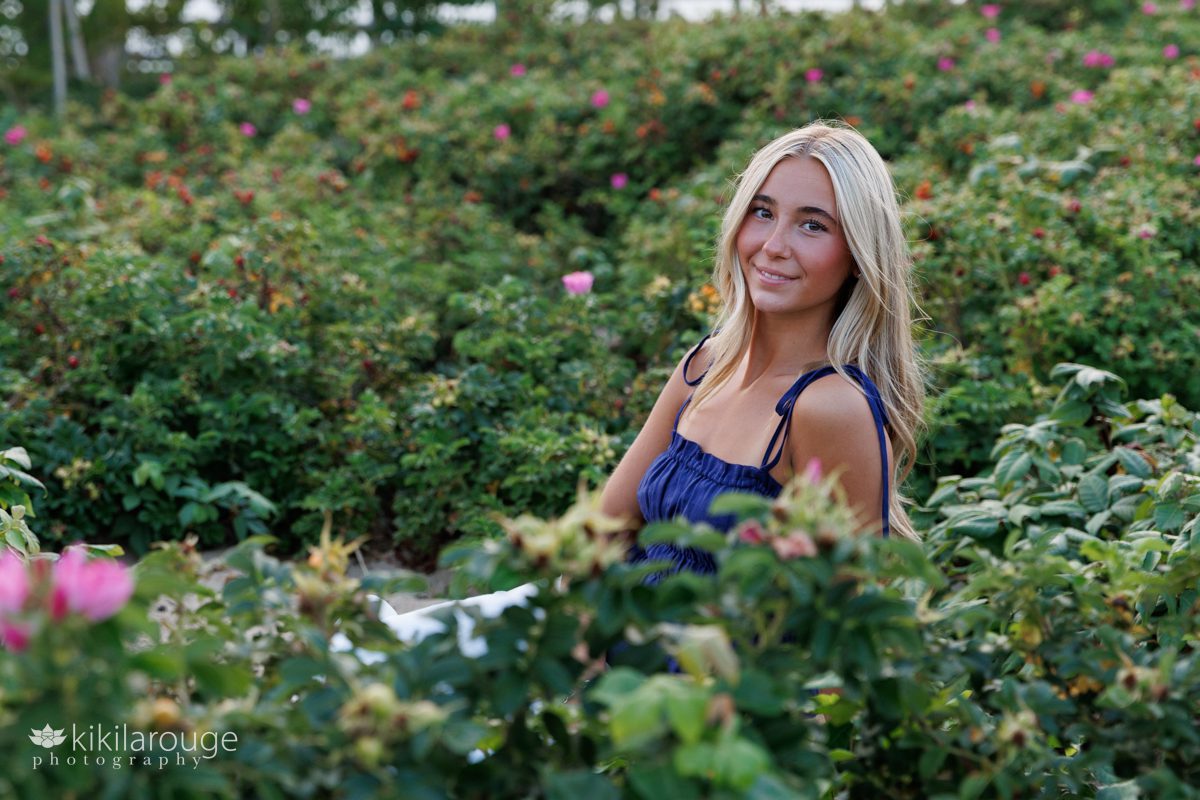 Pretty senior teen girl with long blonde hair sitting in the beach roses at Plum Island Beach
